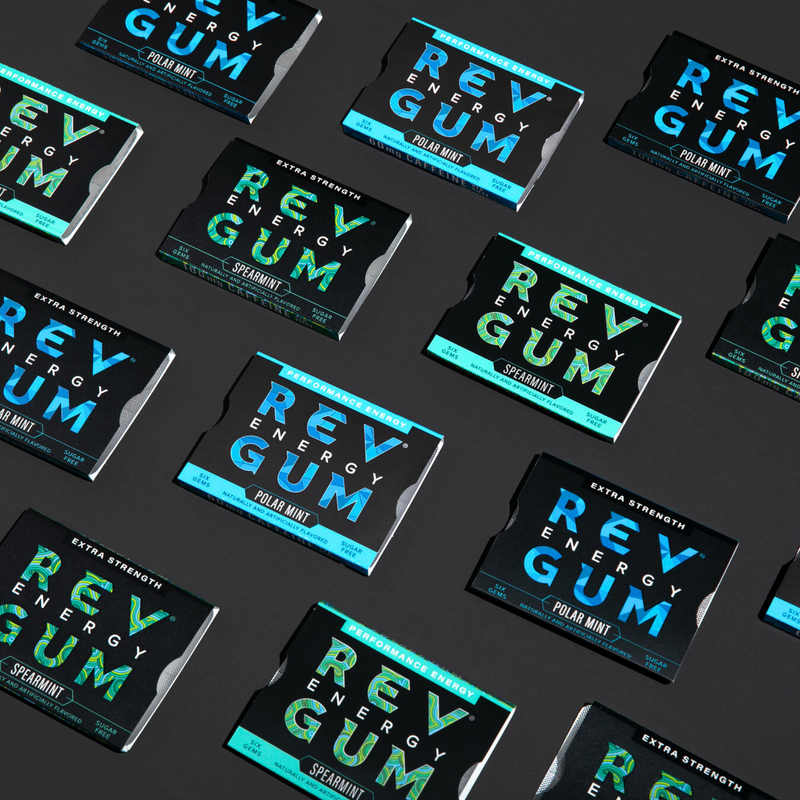 Multiple packages of REV Energy Gum on a dark background