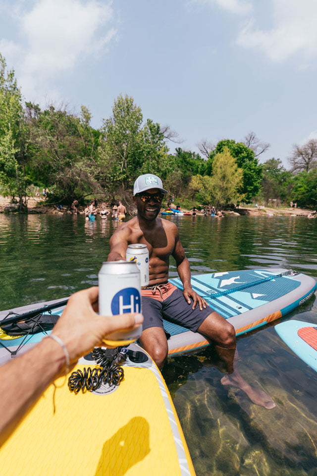 A photo of a man sitting on a stand up paddle board floating on a river.