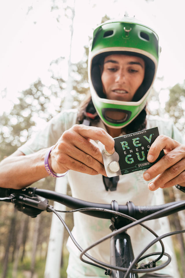 A photo of a woman on a dirt bike opening a pack of gum.
